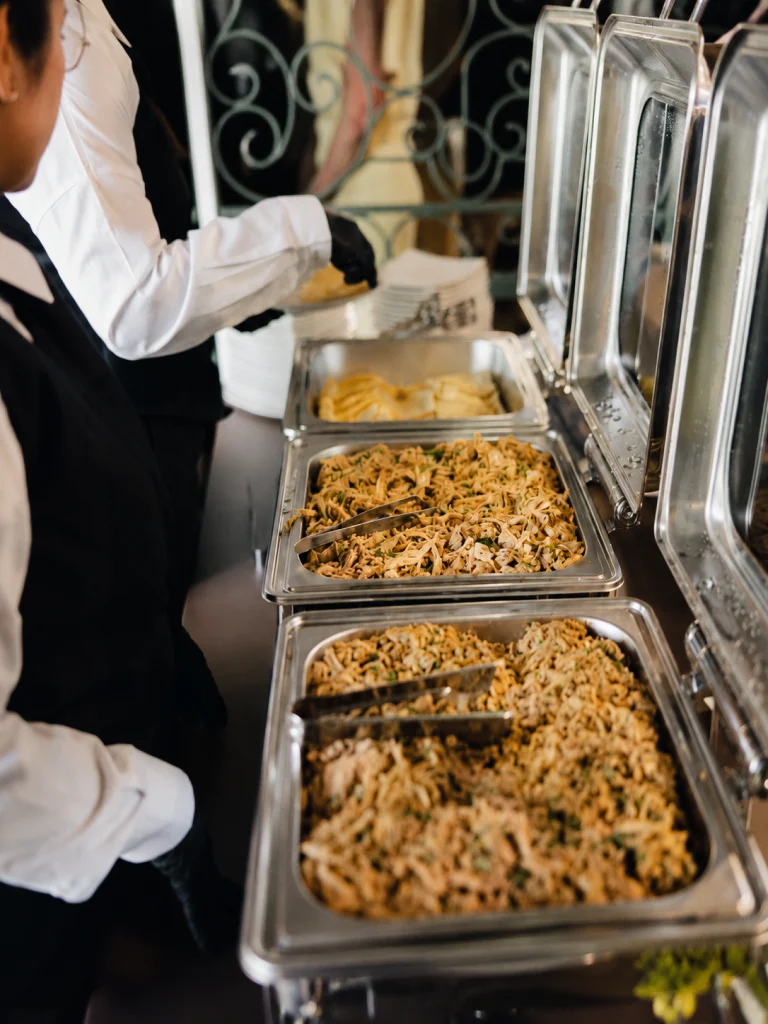 Mesero de Chez Marie atendiendo estaciones de buffet caliente en evento de catering en Panamá — Chez Marie